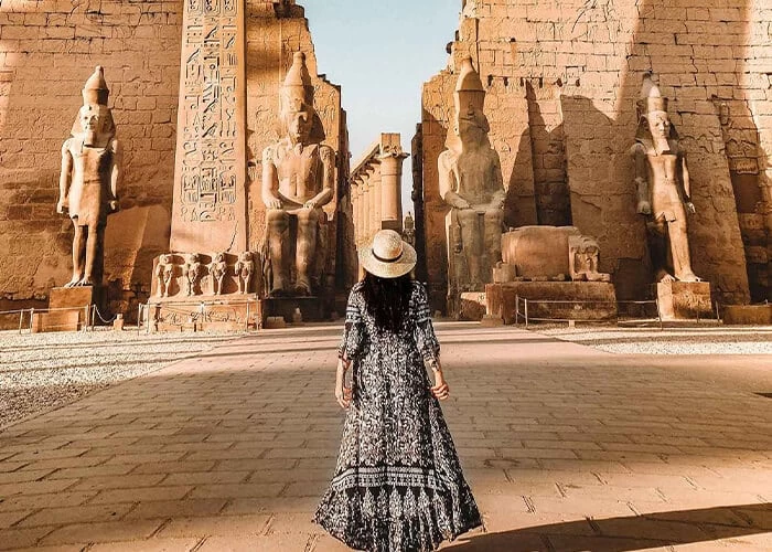 Exclusive luxury tours and events in Egypt with a traveler exploring Luxor Temple and ancient pharaoh statues by Chaya Voyages.