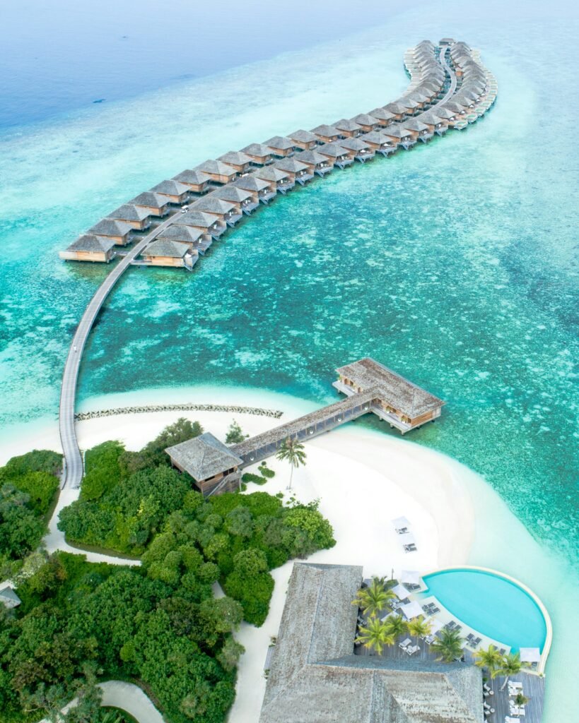 Luxury overwater villas stretching into turquoise ocean lagoon at a private island resort in the Maldives.